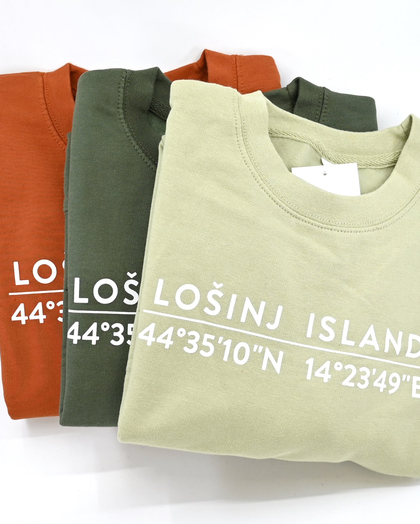 Earthy green, pistachio green and gingerbread sweatshirts with screen printed white Lošinj island coordinates on the back.